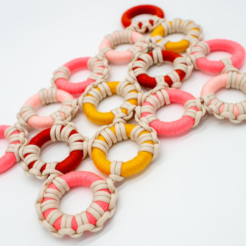Wrapped macrame rings in a variety of warm tones, interconnected with knots.